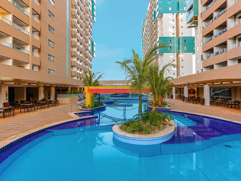 Piscinas do Enjoy Olímpia Park Resort entre as torres de apartamentos, em dia ensolarado